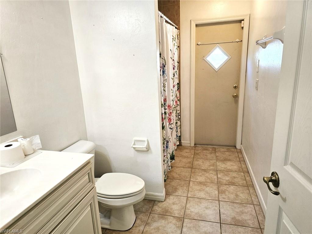 Bathroom featuring curtained shower, vanity, and light tile patterned floors