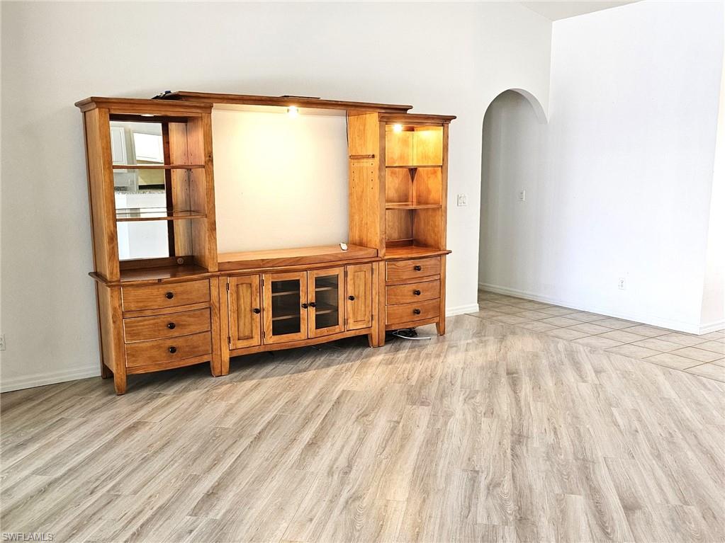 Unfurnished living room featuring light wood finished floors and arched walkways