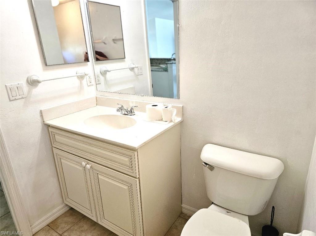 Half bathroom with vanity, a textured wall, and light tile patterned floors