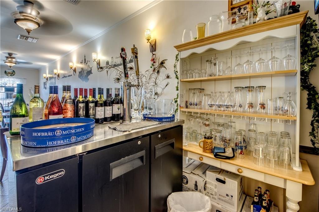 Bar area with stainless steel countertops, dark cabinetry, a ceiling fan, and crown molding