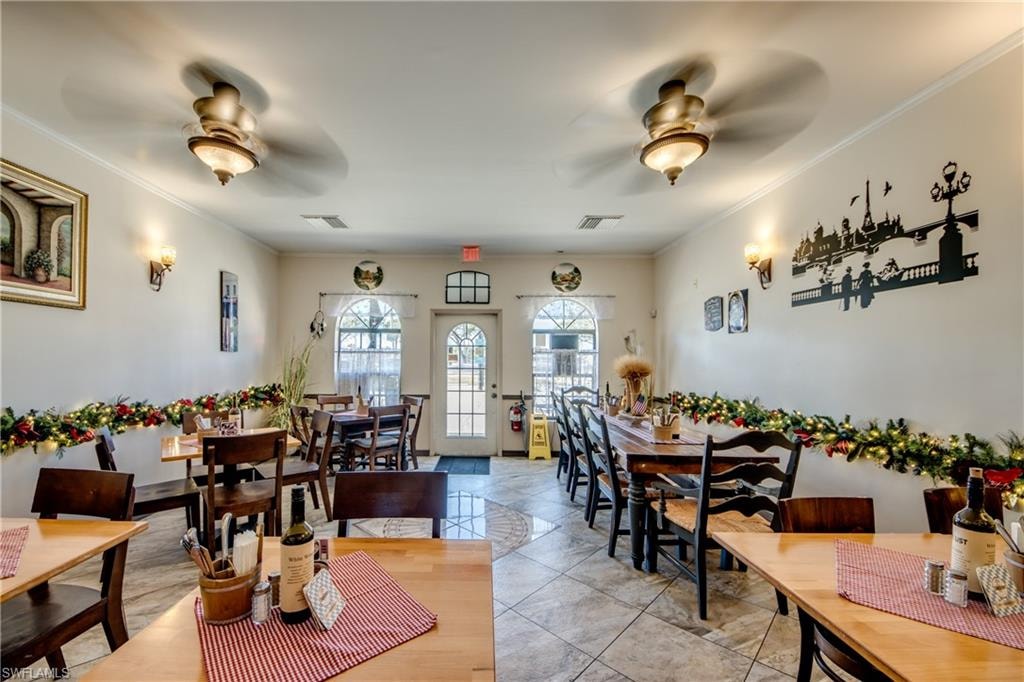 Dining room with a ceiling fan, ornamental molding, and light tile patterned floors