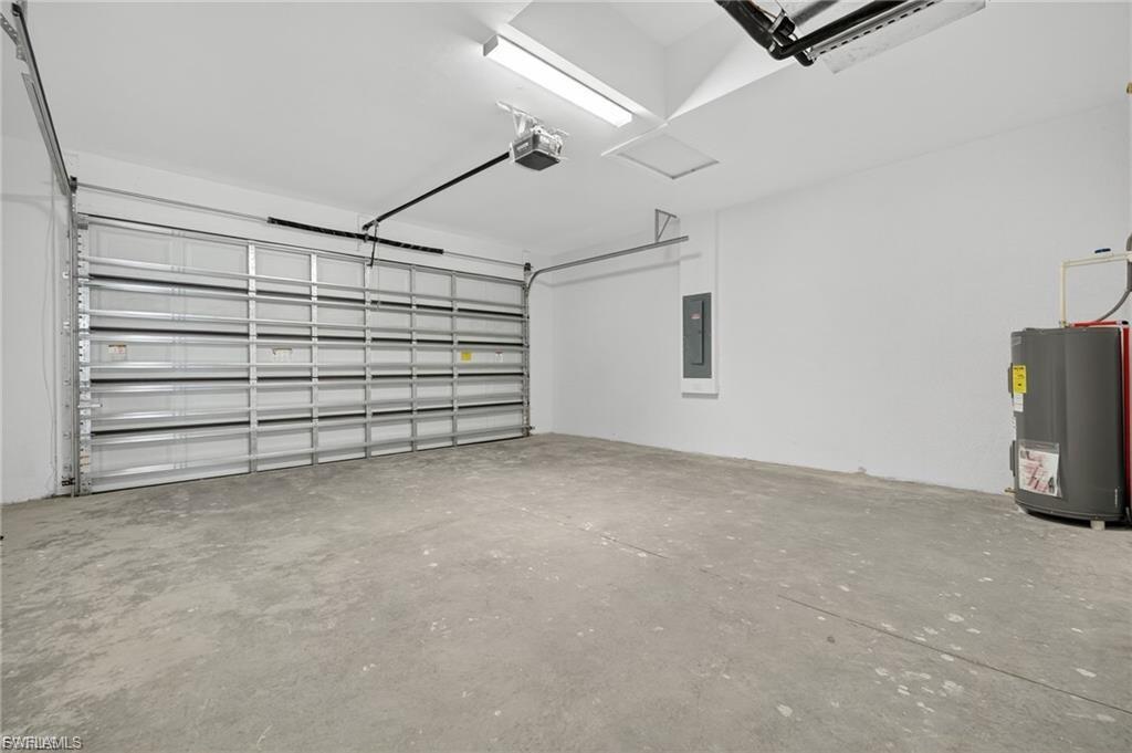 Garage featuring water heater, a garage door opener, and electric panel