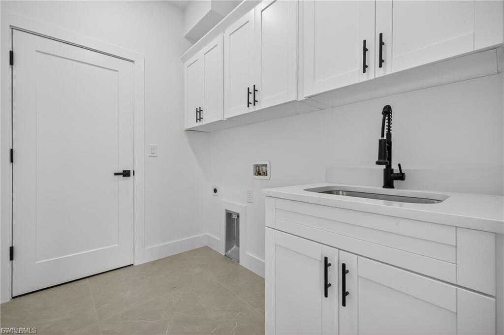 Laundry area featuring hookup for a washing machine, cabinet space, hookup for an electric dryer, and light tile patterned floors