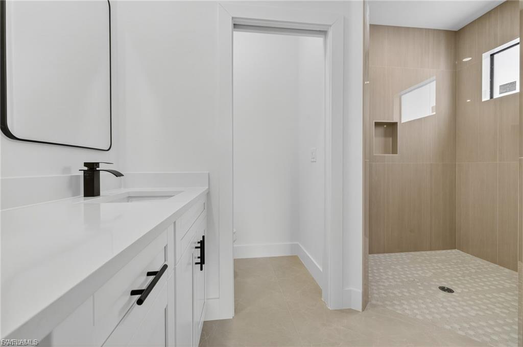 Full bath with walk in shower, vanity, and light tile patterned floors