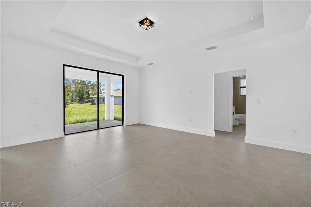 Empty room with a tray ceiling and concrete flooring