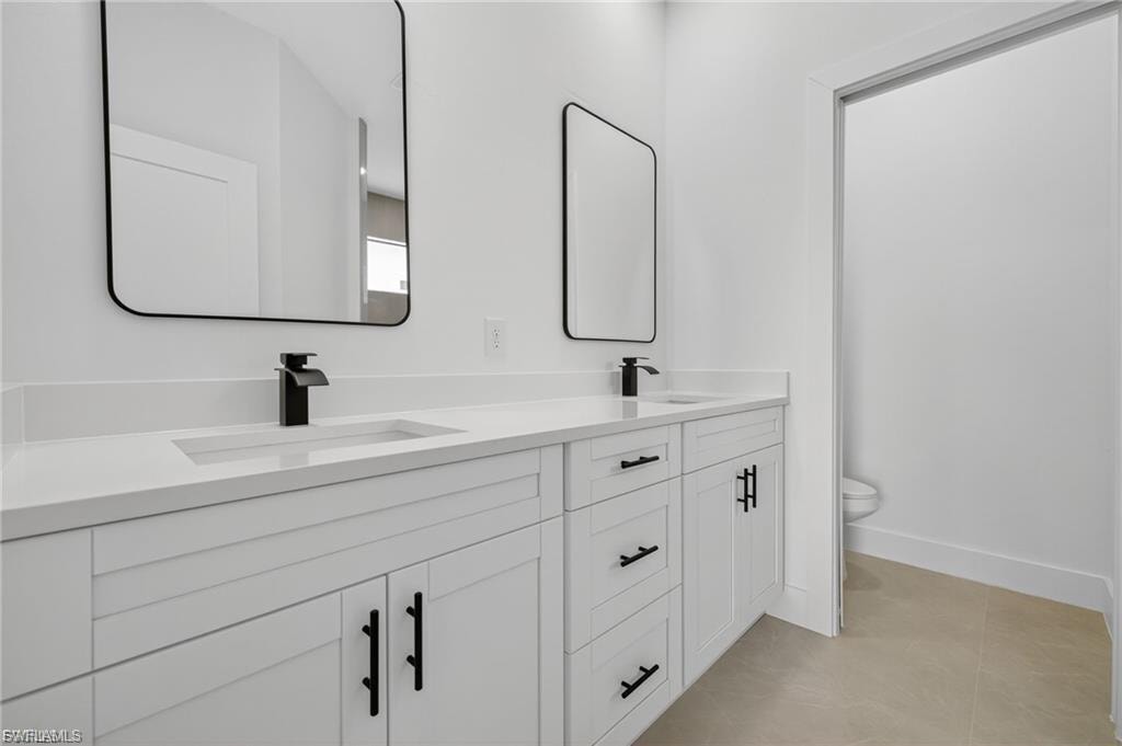 Bathroom with double vanity and light tile patterned flooring
