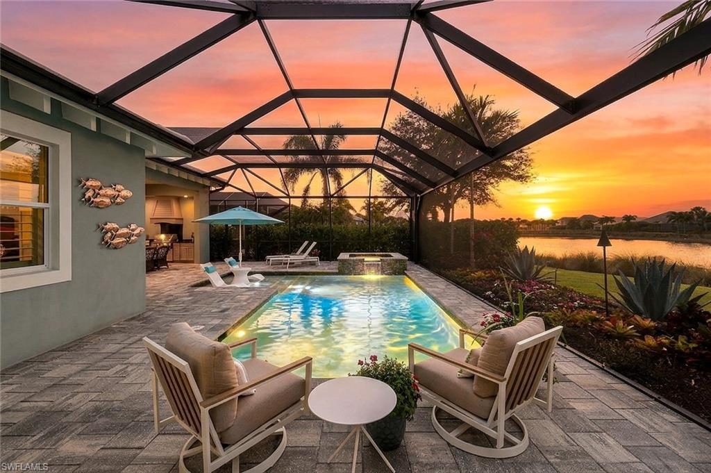 Pool at dusk featuring a pool with connected hot tub, a patio area, a lanai, and a sunroom