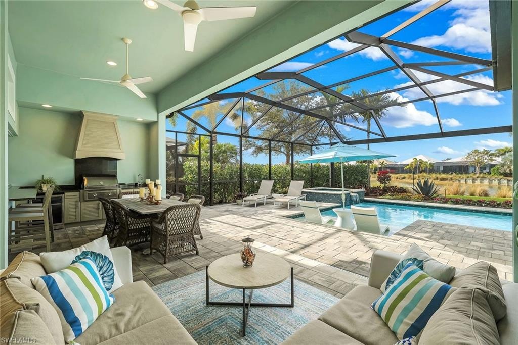 View of patio / terrace with exterior kitchen, a sunroom, a pool with connected hot tub, glass enclosure, and an outdoor living / dining area