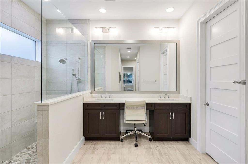 Full bathroom featuring double vanity, a walk in shower, light wood-style flooring, and recessed lighting