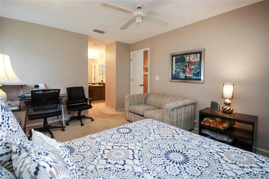 Carpeted bedroom featuring ensuite bath and ceiling fan