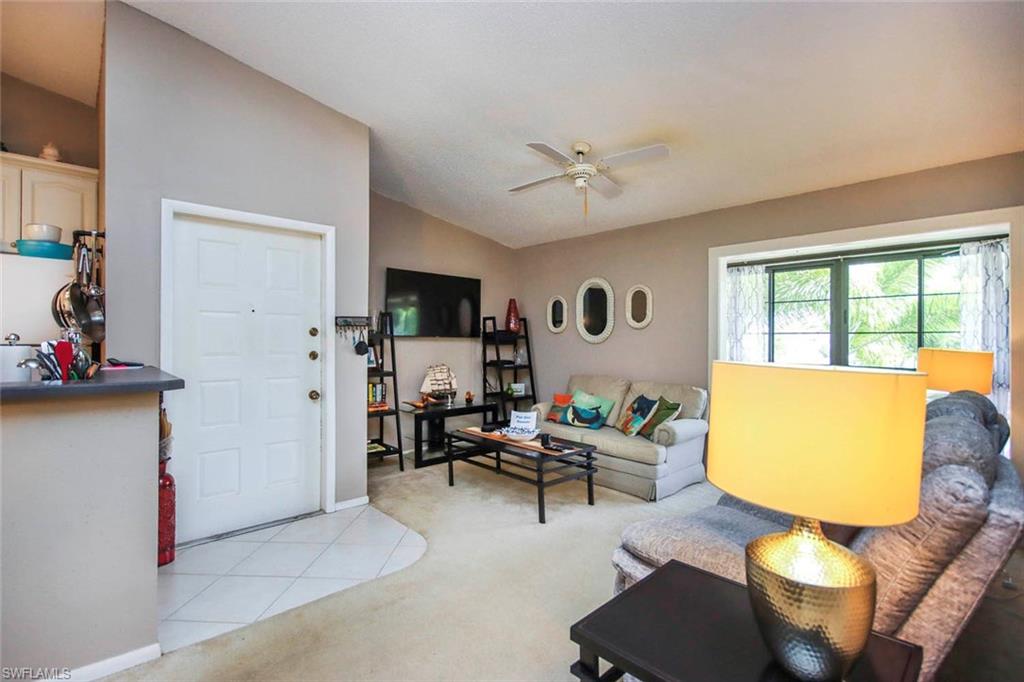 Living room featuring lofted ceiling, light carpet, and ceiling fan