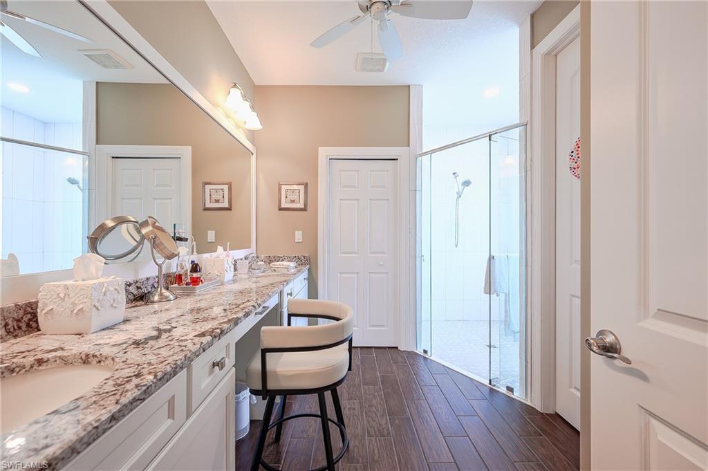 Full bathroom featuring ceiling fan, a shower stall, double vanity, and wood tiled floors