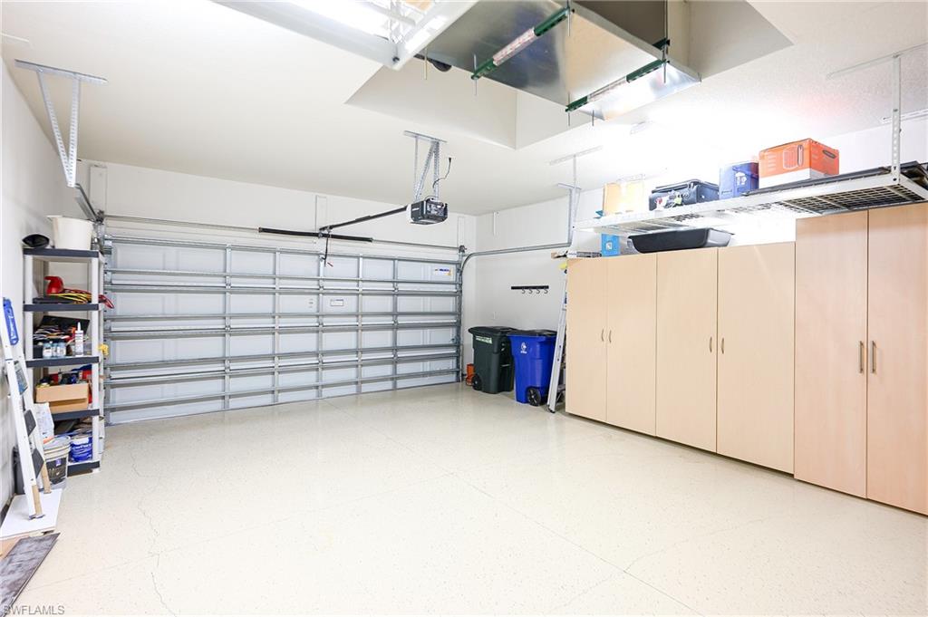 Garage featuring a garage door opener, finished floor and a/c with 1/2 split unit