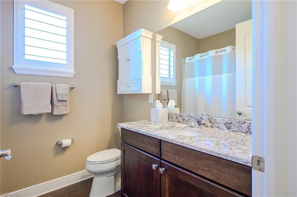 Full bathroom featuring double vanity, spacious closet, a shower and wood-style flooring