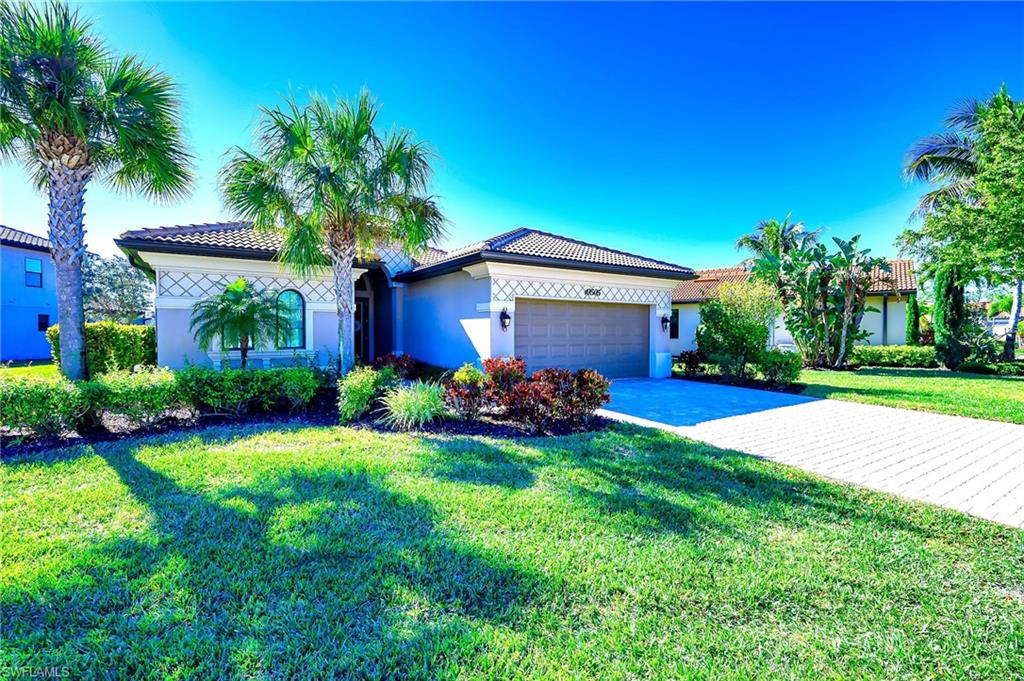 View of front of property featuring a garage, concrete driveway, a tile roof, and a front yard