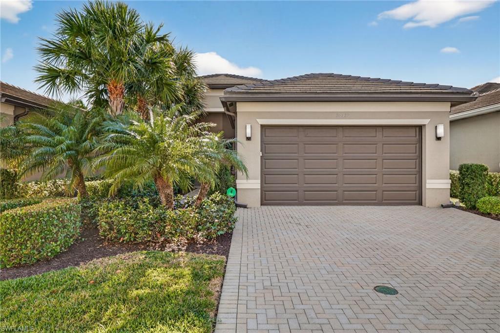 View of front of property with decorative driveway, stucco siding, and an attached garage