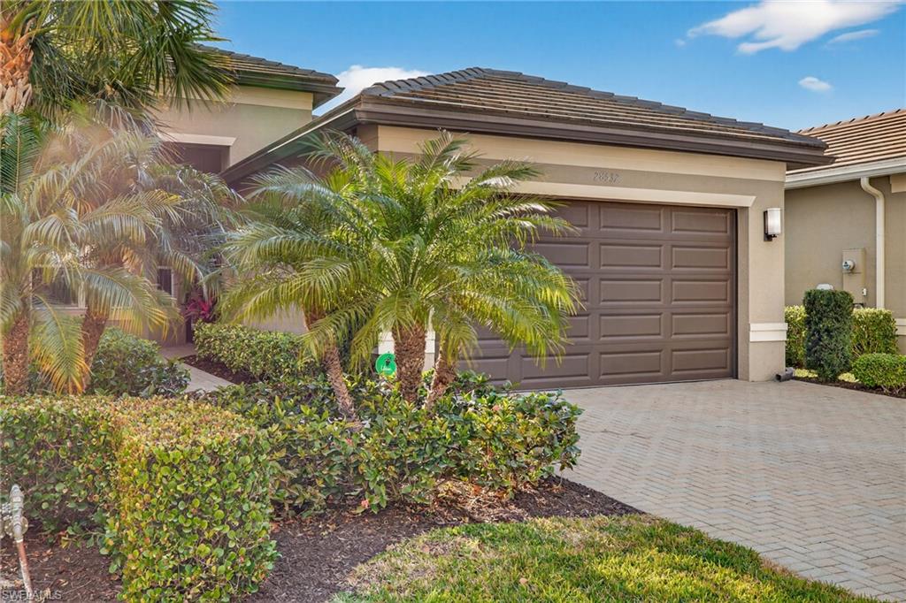 View of front of property featuring decorative driveway, stucco siding, an attached garage, and a tiled roof
