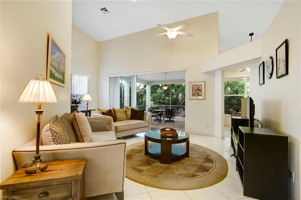 Living area featuring high vaulted ceiling, tile floors, and triple sliders that are impact glass