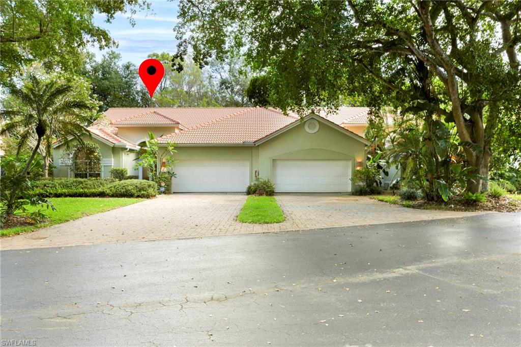 View of front of property with a tile roof, paver driveway, and attached double garage