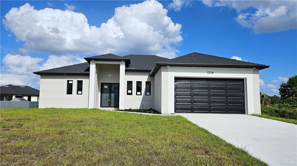 Prairie-style house with stucco siding, a front lawn, a garage, and concrete driveway