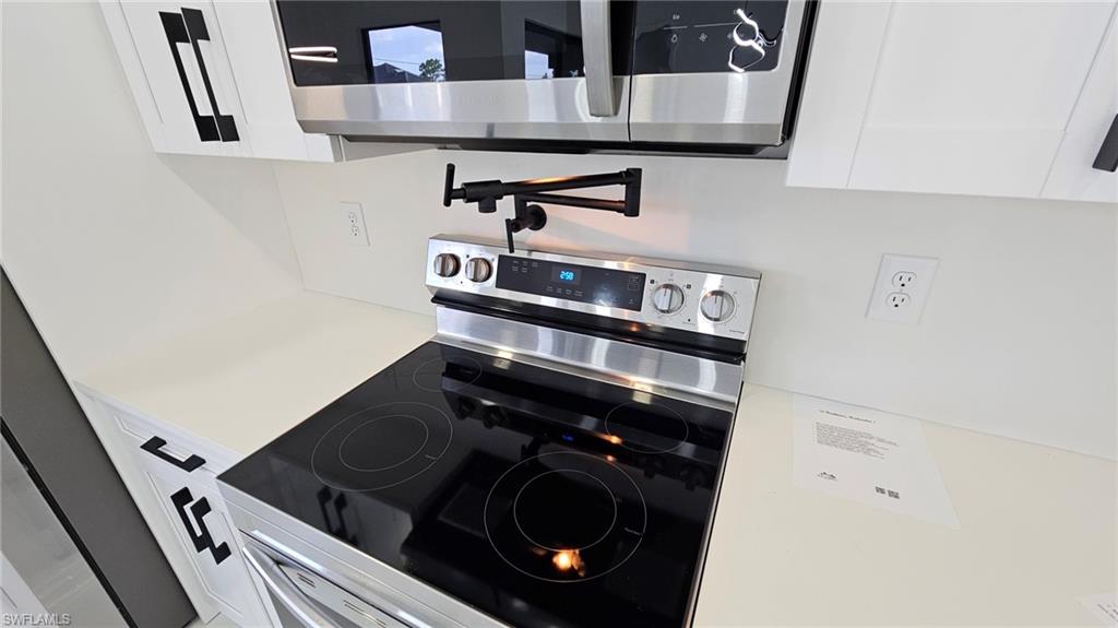 Kitchen featuring stainless steel appliances and white cabinetry