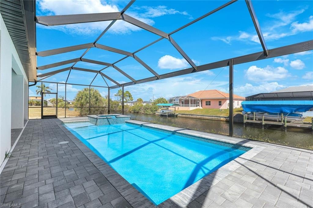 Integrated pool / spa featuring glass enclosure, a patio, a sunroom, a water view, and a boat dock
