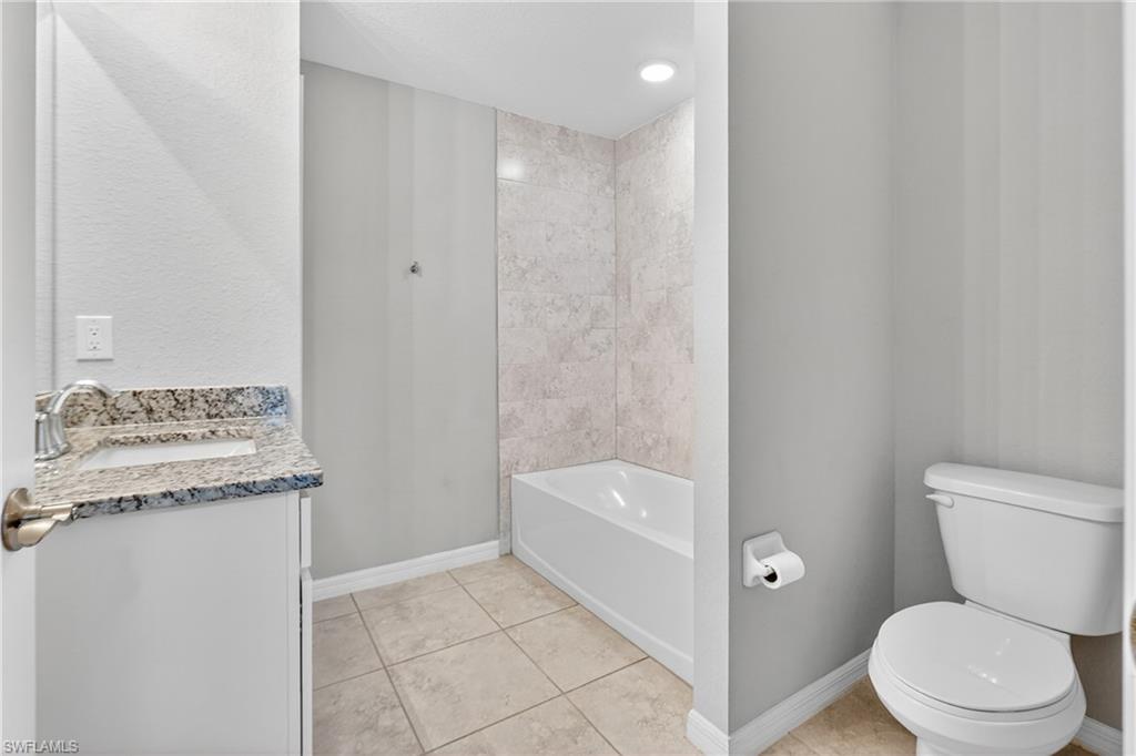Bathroom featuring vanity, light tile patterned floors, a bathtub, and a shower