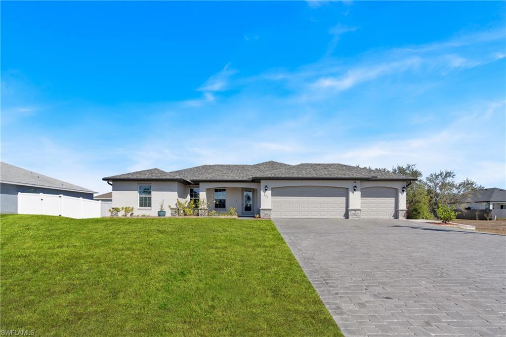 Prairie-style home with stucco siding, a garage, decorative driveway, and stone siding