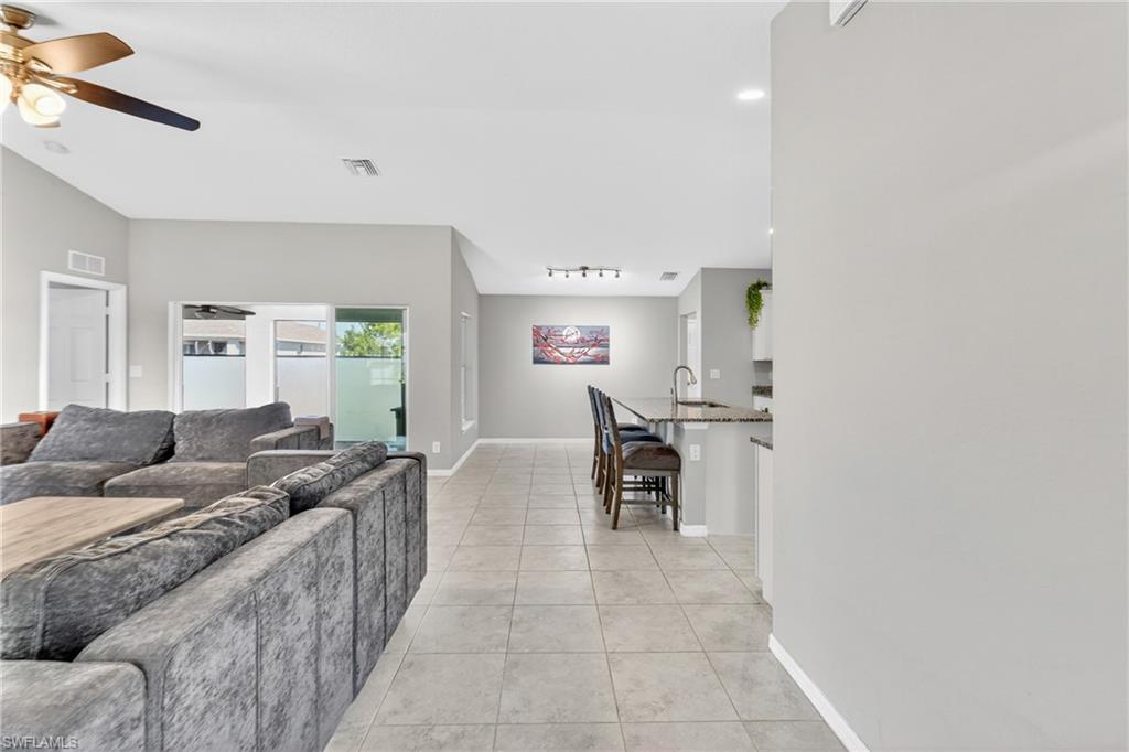 Living area featuring a ceiling fan, light tile patterned flooring, and vaulted ceiling