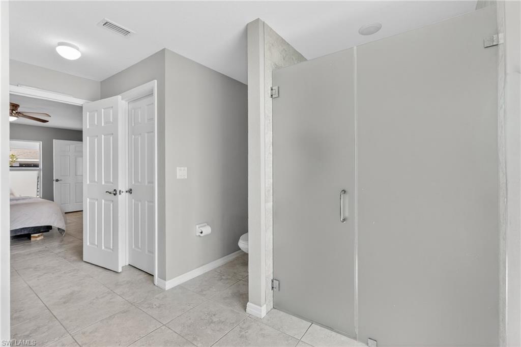 Ensuite bathroom featuring a stall shower, ceiling fan, and light tile patterned floors