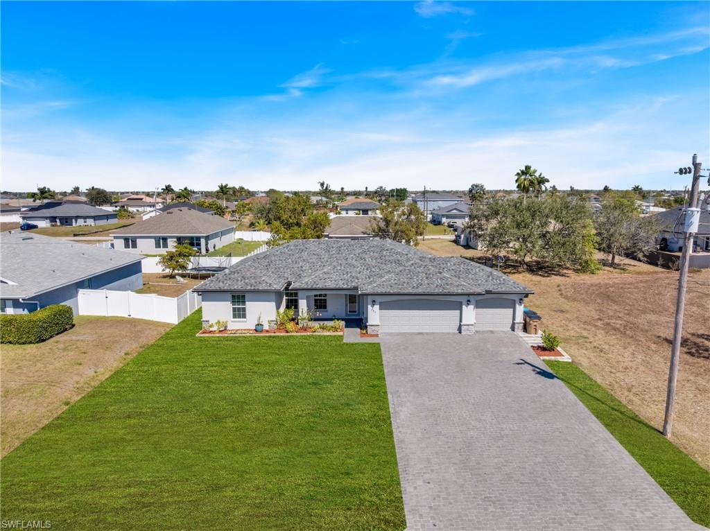 Ranch-style house featuring an attached garage, a residential view, and driveway
