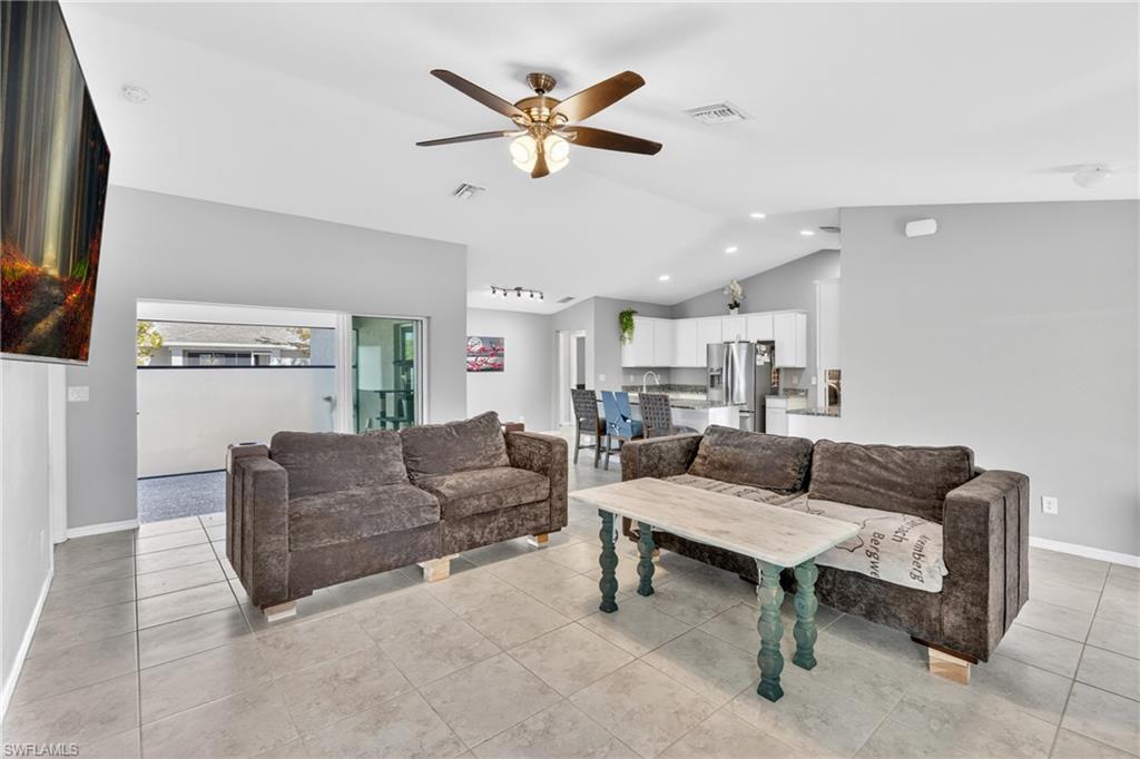 Living area with a ceiling fan, light tile patterned floors, and vaulted ceiling