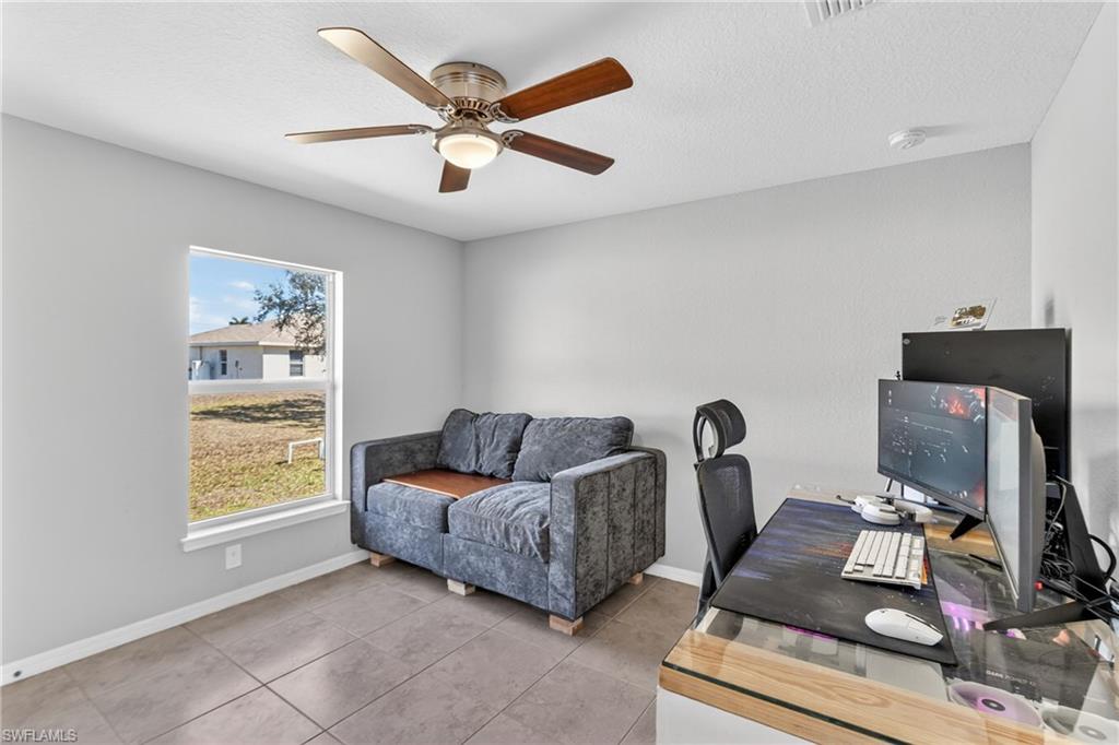 Tiled office with ceiling fan and a textured ceiling