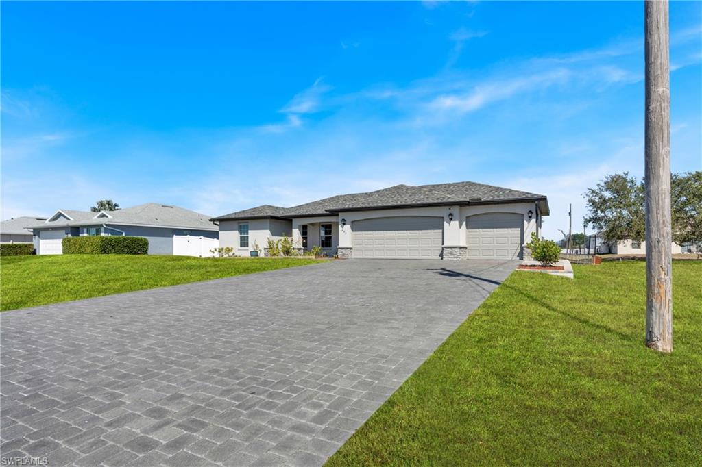 Prairie-style home featuring an attached garage, a front lawn, decorative driveway, and stone siding
