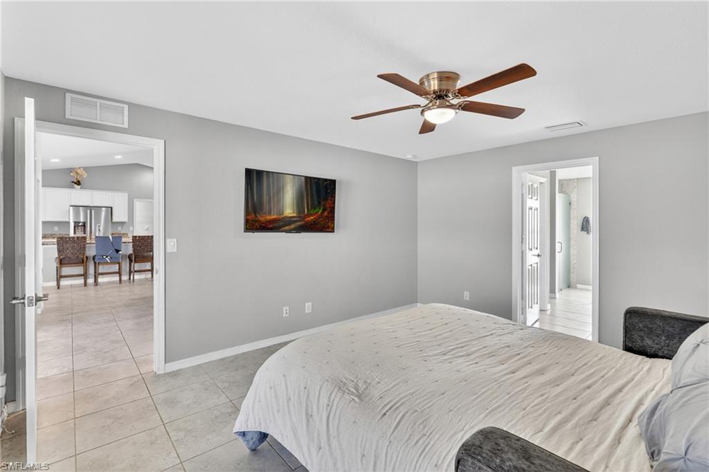 Bedroom with stainless steel refrigerator with ice dispenser, light tile patterned floors, and ceiling fan