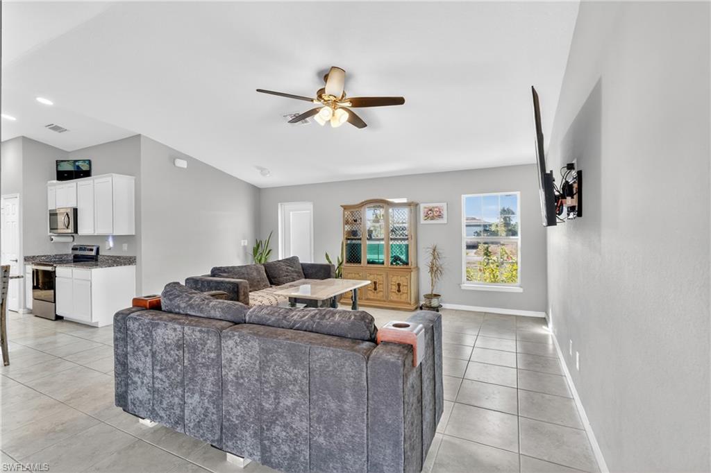 Living area with a ceiling fan, light tile patterned flooring, lofted ceiling, and recessed lighting