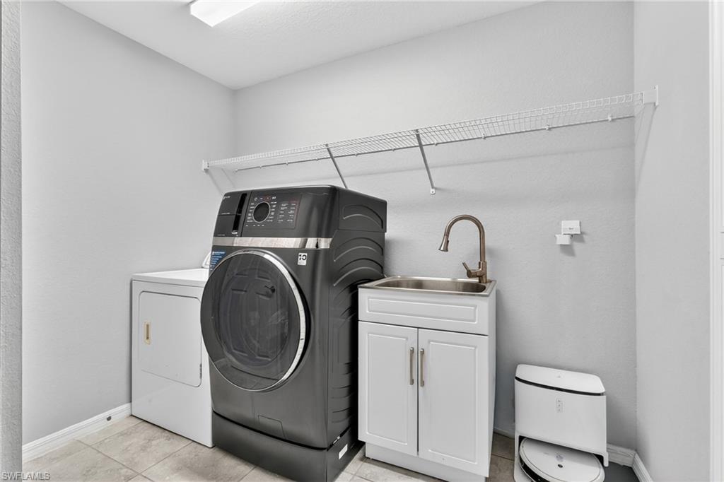 Laundry area featuring washing machine and clothes dryer and light tile patterned floors