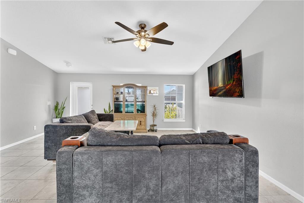 Living area featuring a ceiling fan, lofted ceiling, and light tile patterned floors