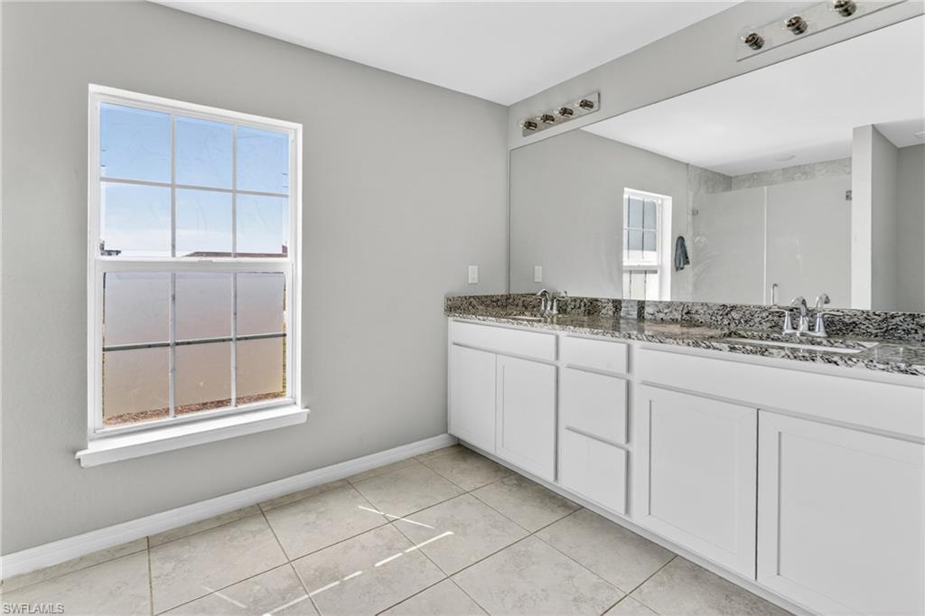 Full bath featuring double vanity, a shower, and light tile patterned floors