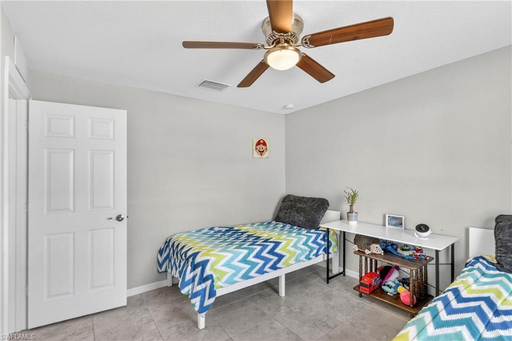 Bedroom with ceiling fan and light tile patterned flooring