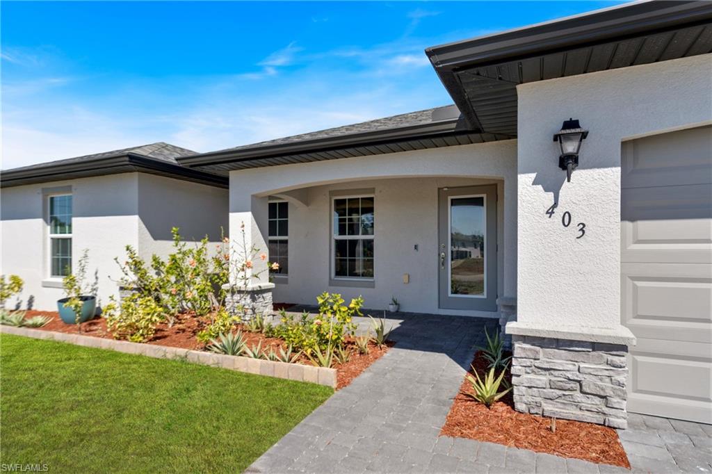 Entrance to property with a porch, stucco siding, and a yard