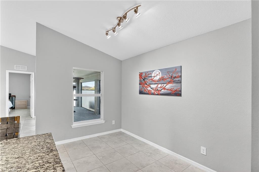 Unfurnished dining area featuring lofted ceiling and light tile patterned floors