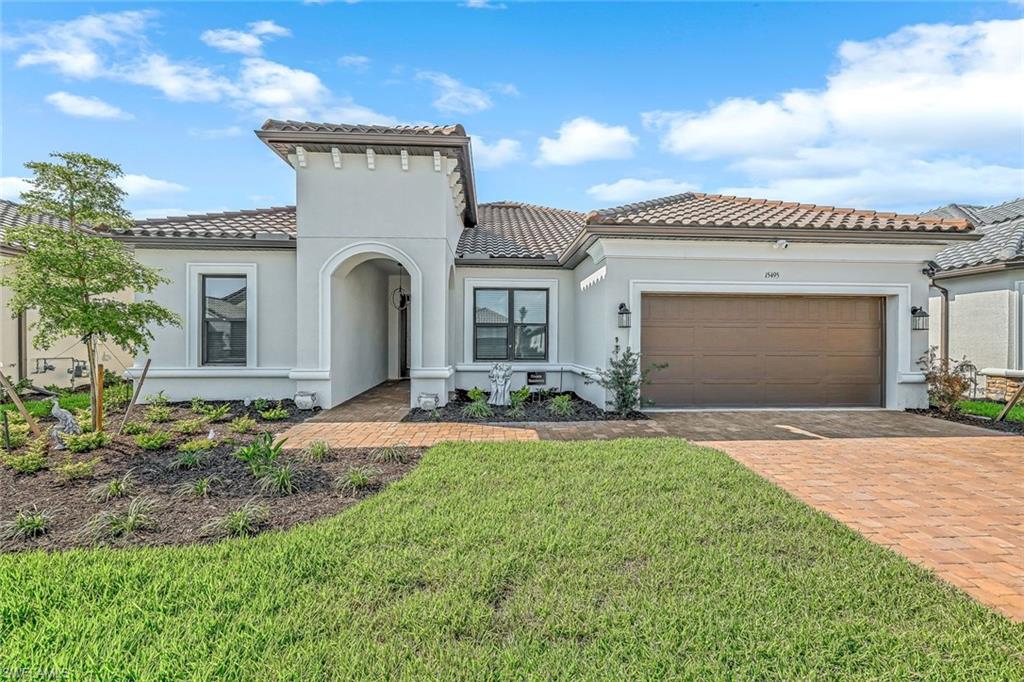 Mediterranean / spanish-style house with a tiled roof, decorative driveway, stucco siding, a garage, and a front yard
