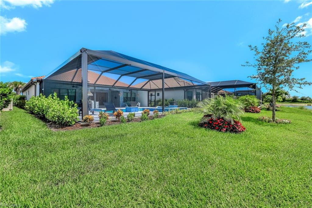 Rear view of property featuring a yard, an outdoor pool, and glass enclosure
