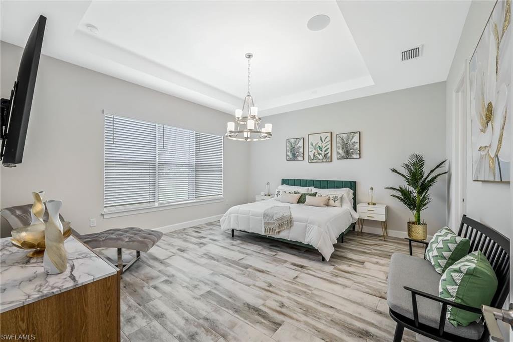 Bedroom with a chandelier, a tray ceiling, and light wood-style floors