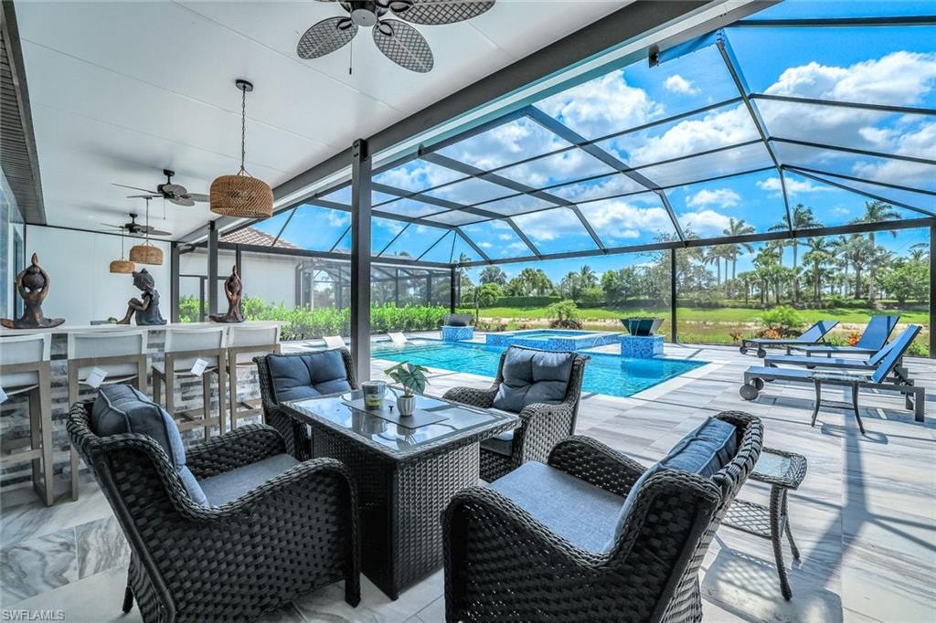 View of patio / terrace featuring ceiling fan, a pool with connected hot tub, and a lanai