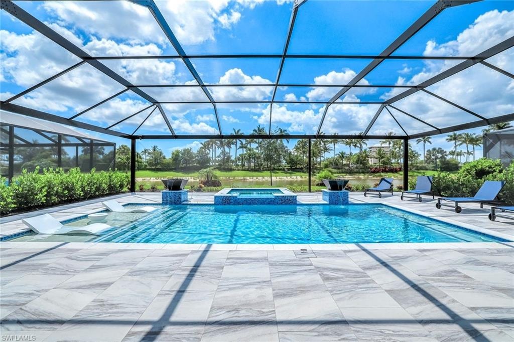View of swimming pool with a pool with connected hot tub, a patio, and a lanai