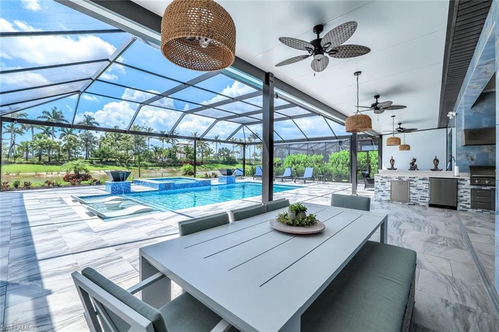 View of patio / terrace with an outdoor kitchen, ceiling fan, a pool with connected hot tub, a lanai, and outdoor dining space
