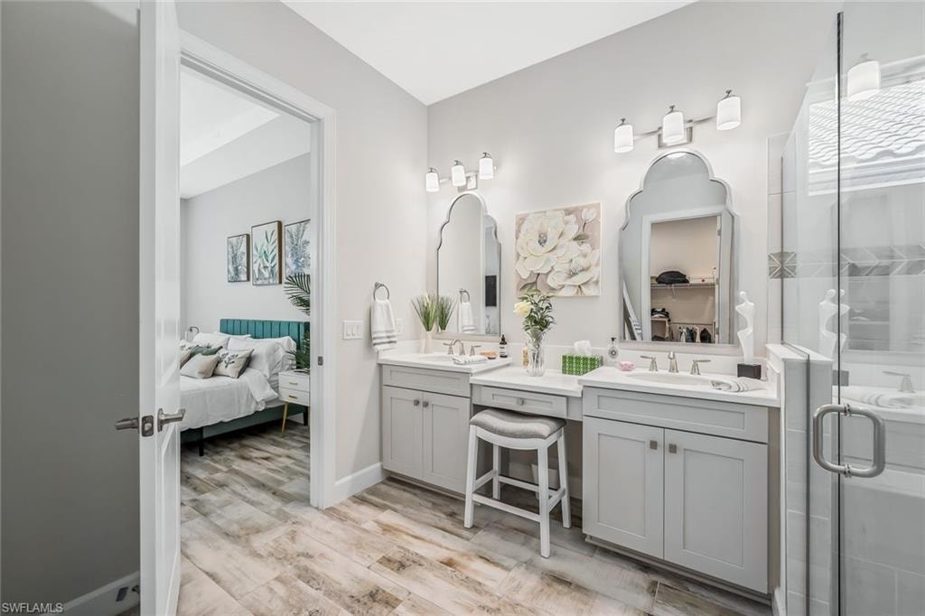 Full bathroom with double vanity, ensuite bathroom, wood finished floors, and a shower stall