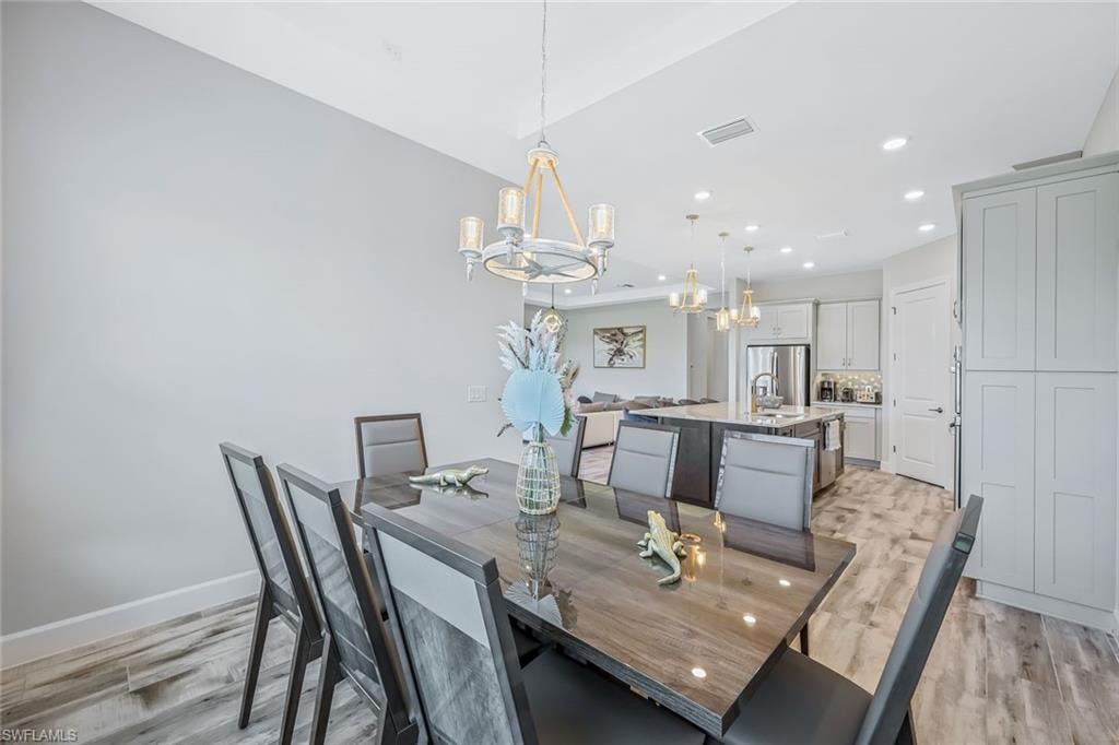 Dining room with a chandelier, light wood finished floors, and recessed lighting